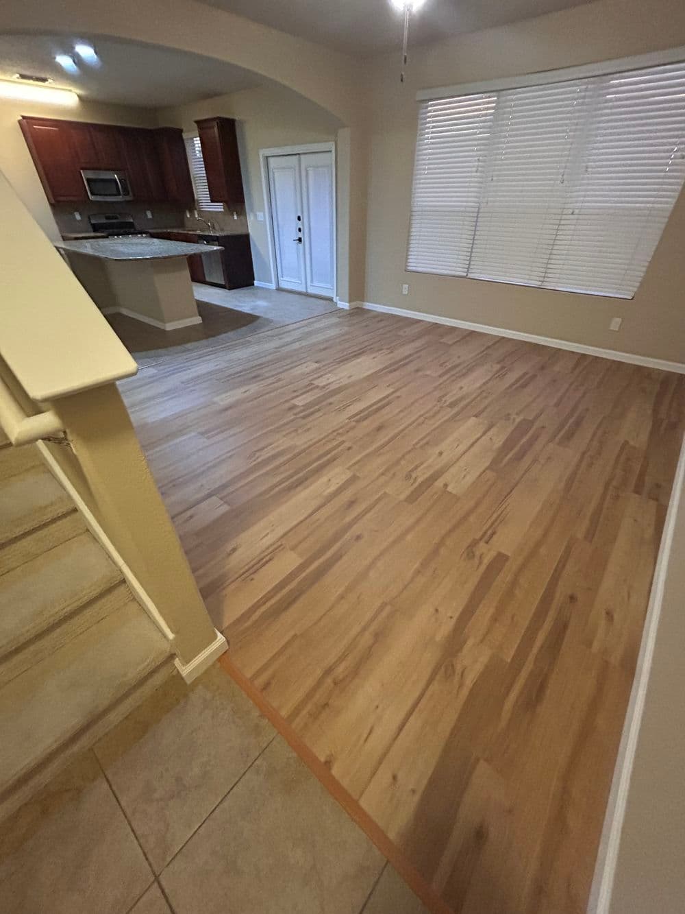 Modern living room with hardwood floors and open kitchen layout, bright natural light.